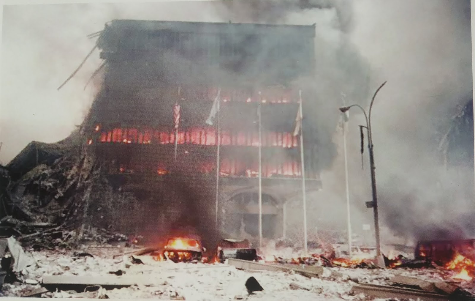 (9/11/01) Flags outside WTC4 not burning. Vehicle with selectively oxidized interior and engine block while nearby paper debris remains white and unburnt, demonstrating selective impedance heating